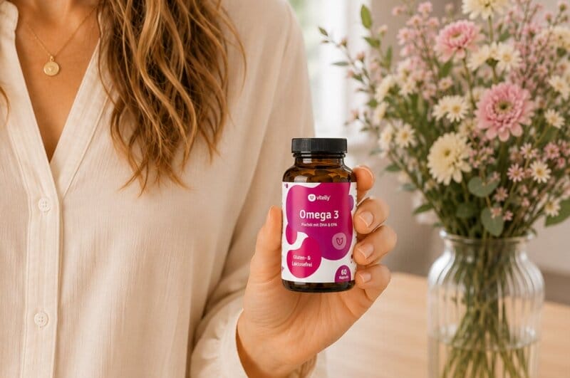 junge Frau hält Omega 3 Fischölkapseln in die Kamera